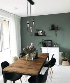 a dining room table with chairs and flowers in a vase on the top of it