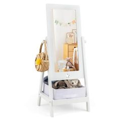 a mirror with stuffed animals in it sitting on a stool next to a basket and dresser