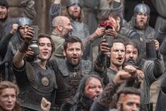 a group of men dressed in medieval armor holding up their cell phones while standing next to each other