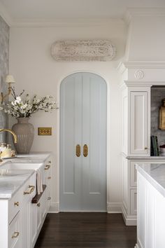 a white kitchen with a blue door and gold handles on the handlebars is shown