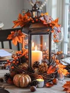 a lantern filled with candles sitting on top of a table covered in leaves and acorns