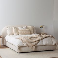 a bed with pillows and blankets on top of it in a room next to a table