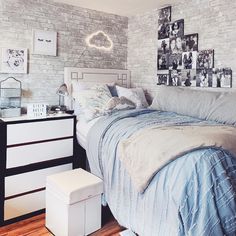 a bedroom with white brick walls and blue comforter on the bed, along with pictures above it