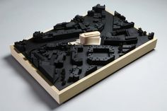 a model of a city made out of legos on a white surface with a wooden frame