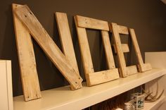 wooden letters that spell out the word nefe on a white shelf in a room