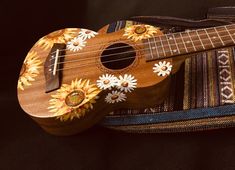 a wooden ukulele with sunflowers painted on it's body and strings