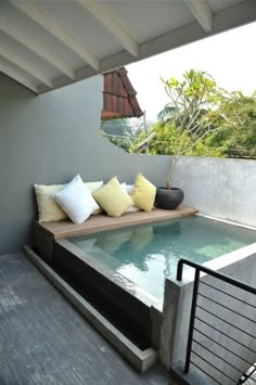 an indoor swimming pool in the middle of a patio with seating and pillows on it