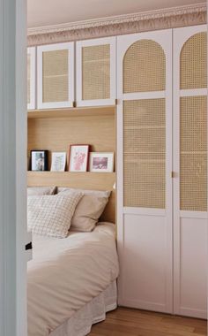 a bed sitting in a bedroom next to a white closet filled with books and pictures