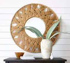 a vase with a plant in it sitting on top of a table next to a mirror