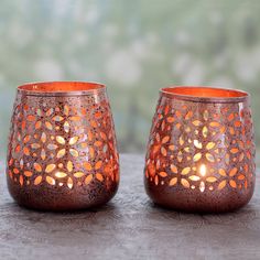 two candles sitting on top of a table next to each other with orange lights in them