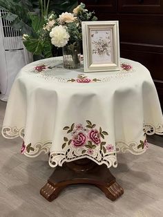 a table topped with a vase filled with flowers next to a framed picture on top of a wooden stand