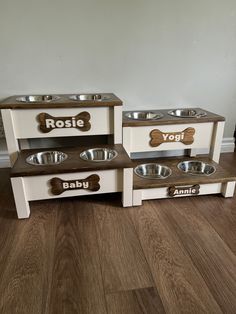 three wooden dog bowls with their names on them and two smaller ones in the middle