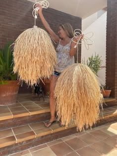 a woman is standing on the steps with two large straw balls in front of her