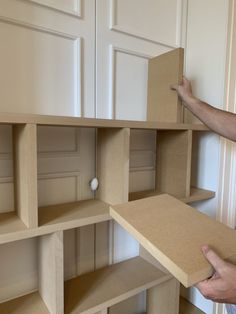 a man is holding up some shelves in his hand and pointing to the bottom shelf