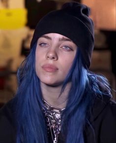 a woman with blue hair wearing a black beanie