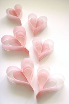 pink paper hearts are arranged on a white surface