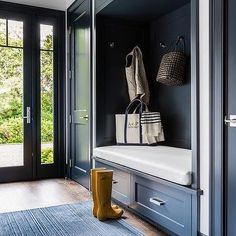 a blue entryway with a bench and two bags hanging on the wall next to it