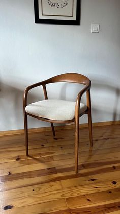 a wooden chair sitting on top of a hard wood floor next to a white wall