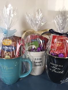 three coffee mugs wrapped in plastic with candy and candies