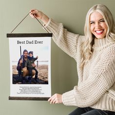 a woman holding up a poster with a man and child on it that says best dad ever