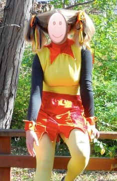 a woman sitting on top of a wooden bench in front of a tree wearing a costume