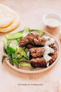 a white plate topped with meat patties and cucumbers