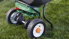 a green wheelbarrow sitting in the grass on top of it's wheels