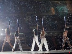 the dancers are performing on stage with their arms in the air as they hold onto poles