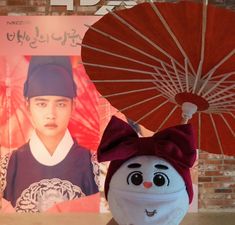 a stuffed animal holding an umbrella next to a photo of a person wearing a hat