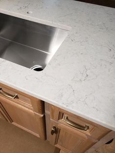 a stainless steel sink sitting on top of a wooden cabinet next to a white counter