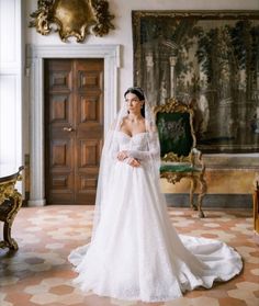 a woman in a white wedding dress standing in front of an ornate wall and chair