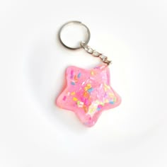 a pink star shaped keychain with sprinkles on it's side