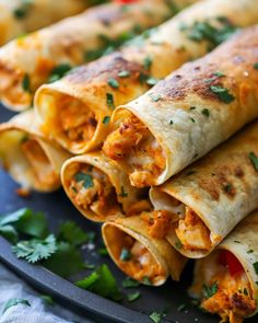 several burritos are stacked on a plate with cilantro garnishes