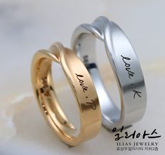 two wedding rings with names engraved on the sides, one in gold and one in silver