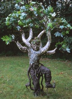 a statue of a man with trees on his head in the middle of a yard