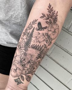 a woman's arm with flowers and mountains in the background on her left forearm