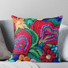 a colorful embroidered pillow sitting on top of a couch