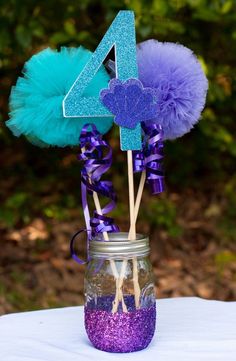 purple and blue flowers in a mason jar with the number four on it's stick