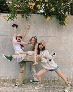 three young people posing in front of a wall with their hands up and arms outstretched