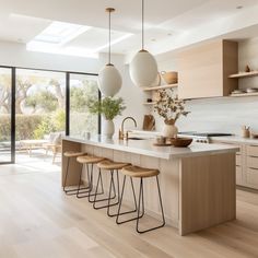 a kitchen with an island and stools in the center, surrounded by glass doors