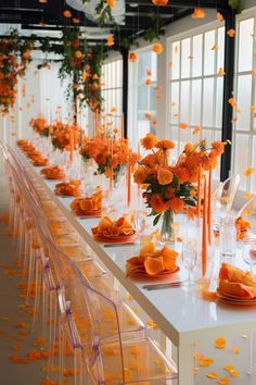 the long table is set with orange flowers and candles