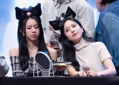 two young women sitting next to each other at a table