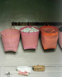 three baskets hanging on the wall with towels in them and one is pink, orange and white