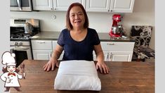 a woman sitting at a kitchen table with a pillow on top of it and an image of a chef in the background