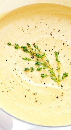 a white bowl filled with soup and garnished with green sprigs