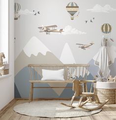 a baby's room with a rocking chair, crib and wallpaper featuring hot air balloons