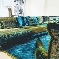 a living room filled with lots of couches and pillows on top of a blue rug