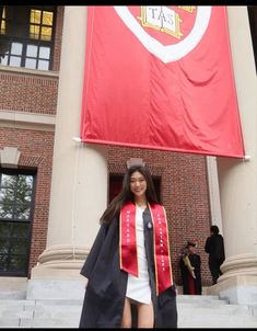 a woman standing in front of a large red flag on the side of a building