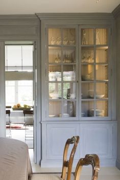 a dining room table and chairs in front of a china cabinet with glass doors on it