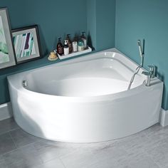 a large white bath tub sitting on top of a tiled floor next to a blue wall